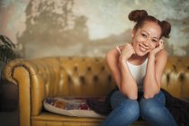 Portrait smiling, confident young woman sitting on sofa — Stock Photo