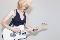Exuberant young woman playing electric guitar — Stock Photo