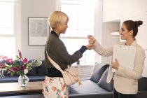 Agente imobiliário dando chaves de apartamento para mulher jovem — Fotografia de Stock