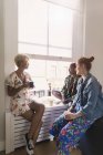 Young women friends talking and drinking tea in apartment window — Stock Photo