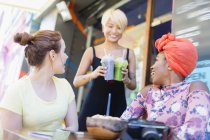 Waitress serving smoothies to women friends at sidewalk cafe — Stock Photo
