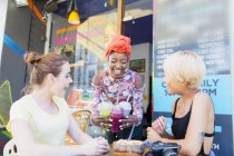 Young women friends enjoying smoothies at sidewalk cafe — Stock Photo