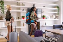 Young women friends with suitcases arriving at house rental — Stock Photo