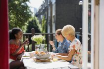 Молоді жінки друзі їдять бранч на сонячному балконі квартири — стокове фото