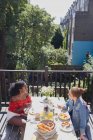 Giovani amiche godendo brunch sul balcone soleggiato appartamento urbano — Foto stock