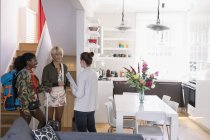 Real estate agent greeting young women friends arriving at house rental — Stock Photo