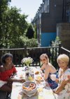 Portrait smiling young women friends enjoying brunch on sunny apartment balcony — Stock Photo