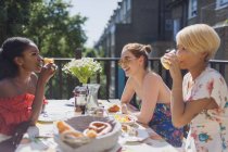 Молоді жінки друзі насолоджуються обідом на сонячному балконі квартири — стокове фото