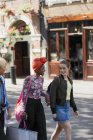 Young women friends shopping, walking on urban street — Stock Photo