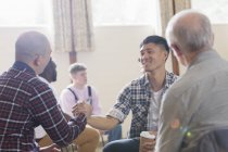 Men shaking hands in group therapy in community center — Stock Photo