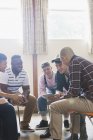 Men with digital tablet talking in group therapy circle — Stock Photo