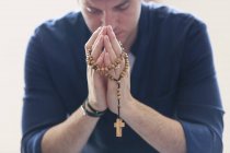 Serene man praying with rosary — Stock Photo