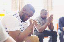 Человек молится с четками в молитвенной группе — стоковое фото