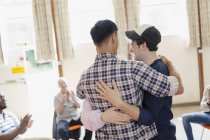 Homens abraçando em terapia de grupo — Fotografia de Stock