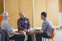 Мужчины разговаривают и слушают в групповой терапии — стоковое фото