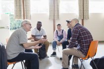 Hommes parlant et écoutant en thérapie de groupe — Photo de stock
