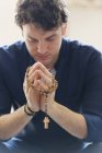 Serene man praying with rosary — Stock Photo