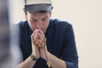 Человек молится с четками — стоковое фото
