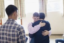 Männer umarmen sich in Gruppentherapie — Stockfoto
