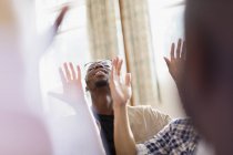 Smiling man with arms raised praying in prayer group — Stock Photo