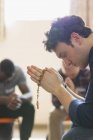 Gelassener Mann betet mit Rosenkranz in Gebetsgruppe — Stockfoto