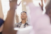 Serene man praying with arms raised in prayer group — Stock Photo