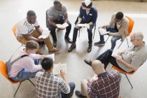 Hombres leyendo y discutiendo la Biblia en círculo de grupo de oración - foto de stock