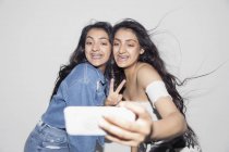 Безтурботні підліткові сестри-близнюки з брекетами, що приймають селфі зі смартфоном — стокове фото