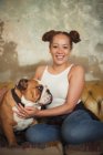 Портрет улыбающейся молодой женщины, ласкающей собаку на диване — стоковое фото