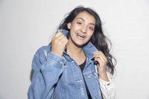 Портрет счастливая, уверенная девочка-подросток с брекетами в джинсовой куртке — стоковое фото