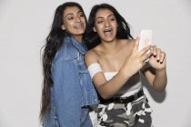Teenage twin sisters taking selfie with smart phone — Stock Photo