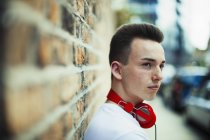 Adolescent sérieux avec écouteurs détournant les yeux — Photo de stock