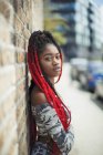 Portrait confident young woman with long red braids on urban sidewalk — Stock Photo