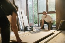 Trabajadores de la construcción levantando tablero de madera en casa - foto de stock