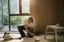 Trabalhador da construção que mede a placa de madeira na casa — Fotografia de Stock