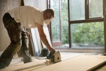 Bauarbeiter schneidet mit Elektrosäge Holzbretter im Haus — Stockfoto