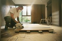 Bauarbeiter mit Tätowierungen schneidet mit Tischkreissäge Holzbretter im Haus — Stockfoto