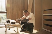 Trabalhador da construção civil com tatuagem que mede a placa de madeira na casa — Fotografia de Stock