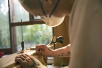 Primo piano muratore con tatuaggi esaminando bordo di legno — Foto stock