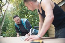 Bauarbeiter messen Holz in Einfahrt — Stockfoto