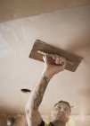 Trabalhador da construção civil com teto de reboco de tatuagem — Fotografia de Stock