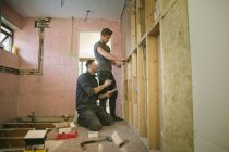 Ouvriers de la construction encadrant à l'intérieur de la maison — Photo de stock