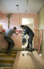 Trabalhadores da construção usando ferramenta de nível em casa — Fotografia de Stock
