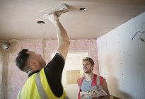 Construction workers plastering ceiling — Stock Photo