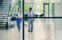Empresários caminhando e conversando no lobby do escritório — Fotografia de Stock