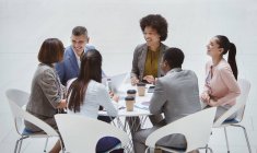 Empresários sorridentes reunidos à mesa redonda — Fotografia de Stock