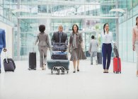 Business people walking with luggage in airport — Stock Photo