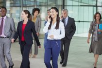 Smiling businesswoman talking on cell phone and walking — Stock Photo