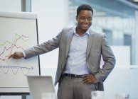Smiling businessman at flip chart leading conference room meeting — Stock Photo