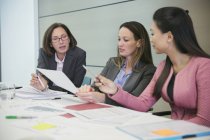 Empresárias discutindo papelada em reunião de sala de conferências — Fotografia de Stock